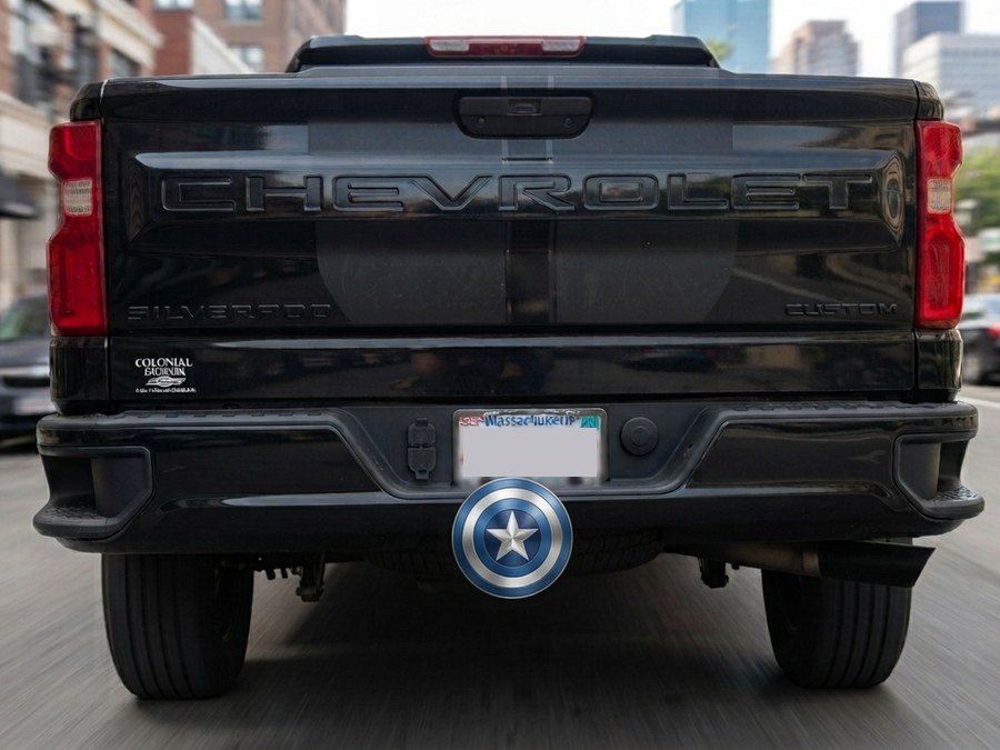 Old Glory shield hitch cap mounted on a black truck's receiver hitch
